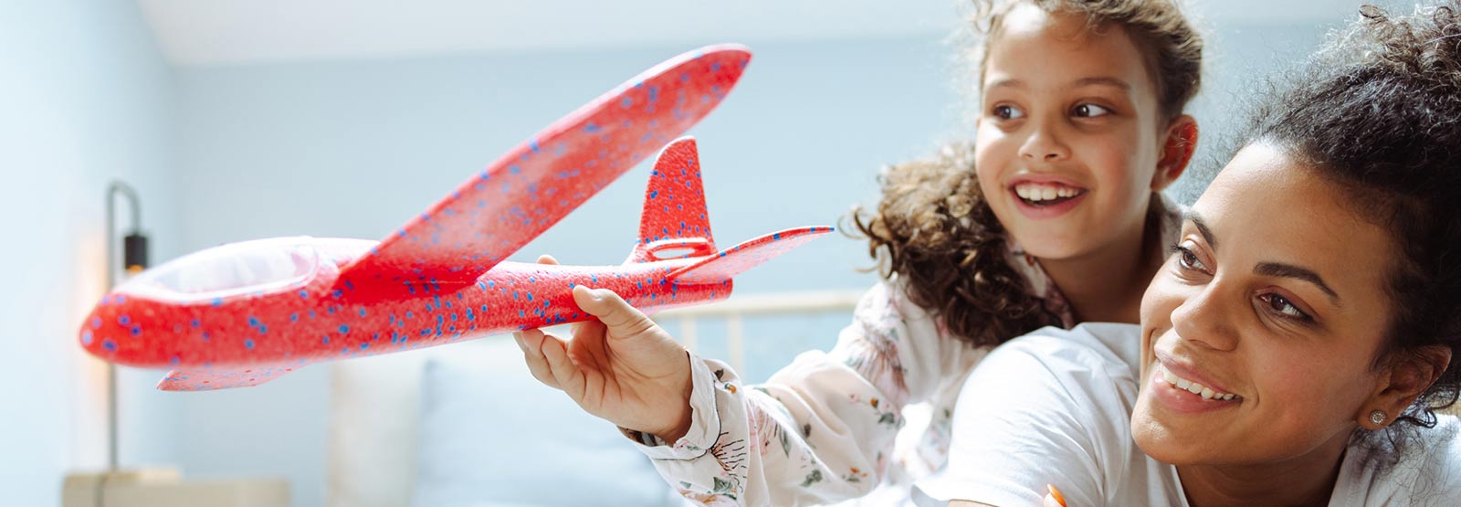 Mother and daughter playing with toy plane.