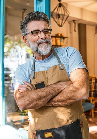 Small business owner leaning against the door of their business.