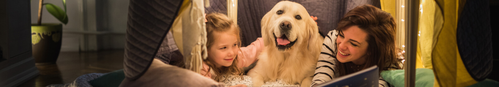 Mother and daughter camping indoors with their dog.