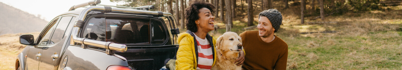 Couple sitting on the back of their truck with their dog.