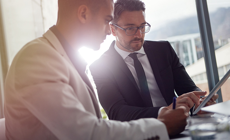 Businessmen meeting and looking at a tablet.